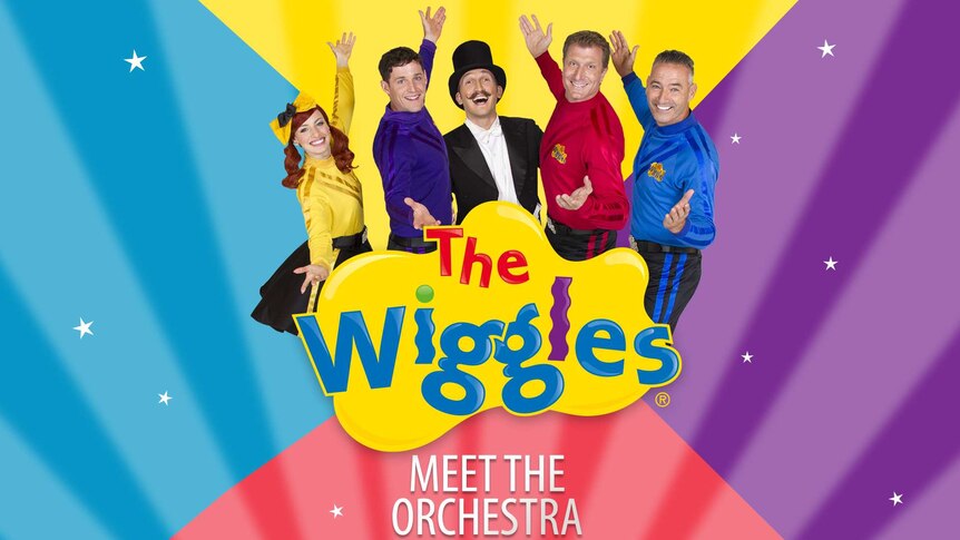 An orchestrator is flanked by The Wiggles members posing with their arms open