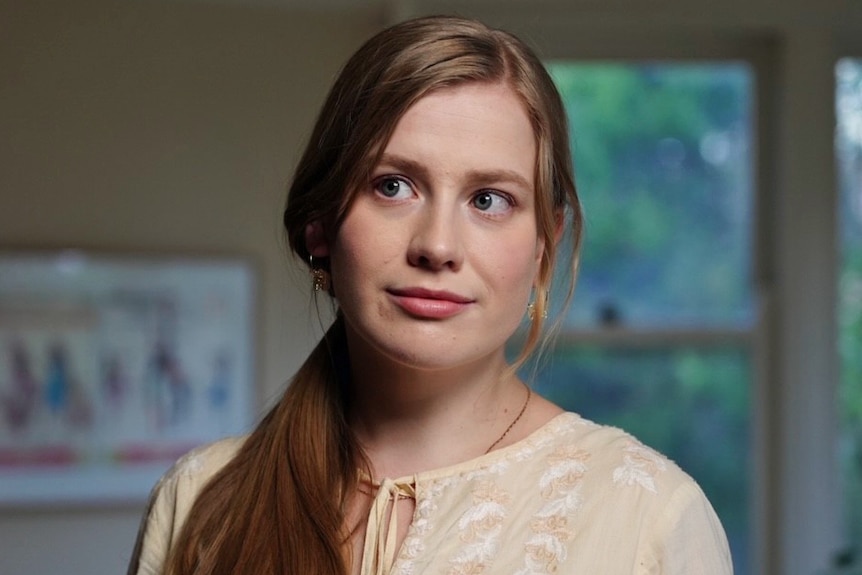 A woman wearing a yellow top looks to her right.