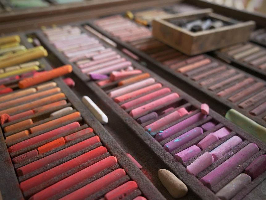 A collection of different coloured pastels in a box.