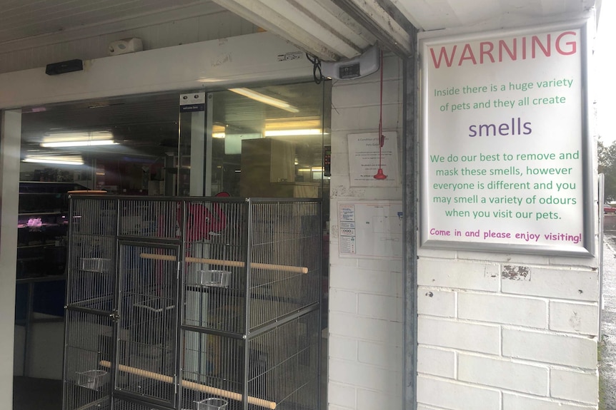 A sign at the entrance to a pet shop warning patrons about the odours within.