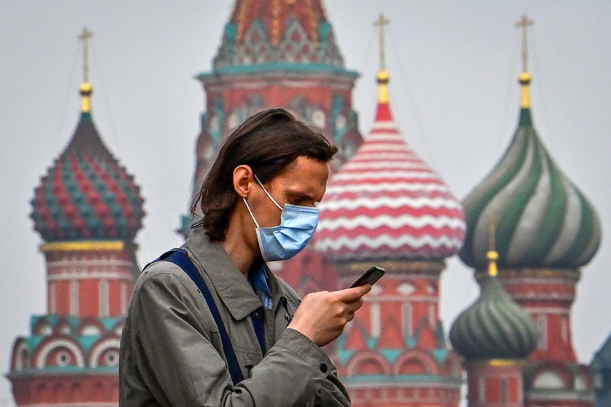 A man on his mobile phone in central Moscow with a colourful cathedral in the background