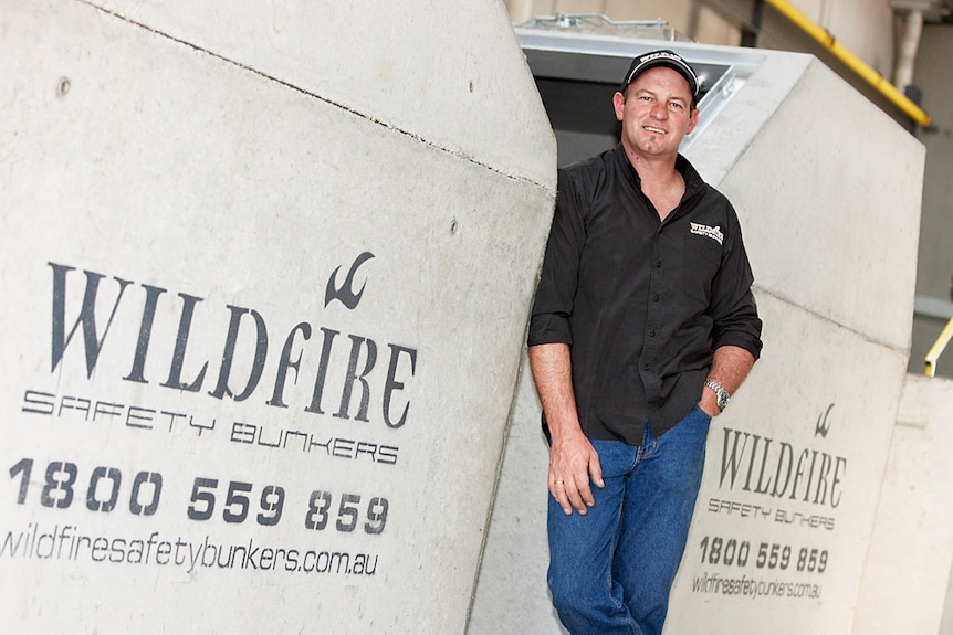 A man stands between concrete with the words "wildfire safety bunkers".
