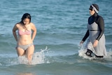 Woman in a bikini next to a woman in a burkini