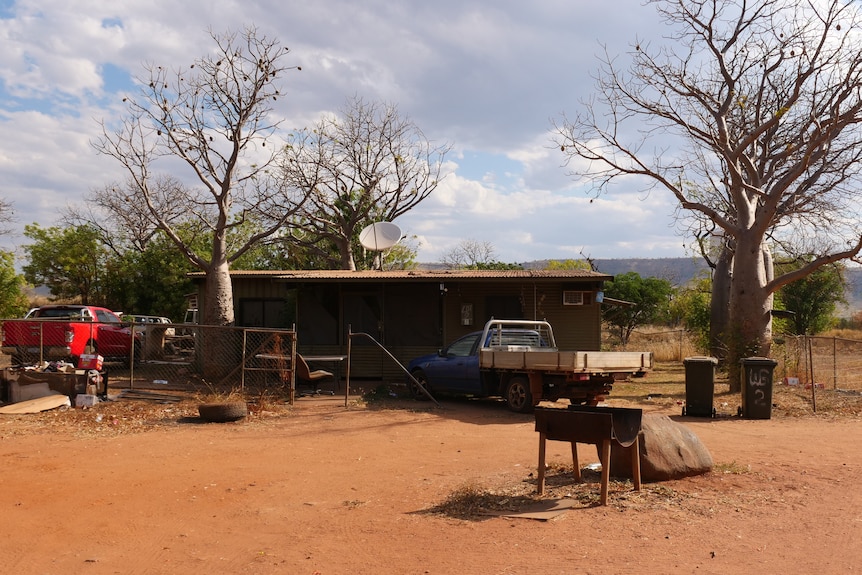 A ramshackle house amid red dirt in a country town