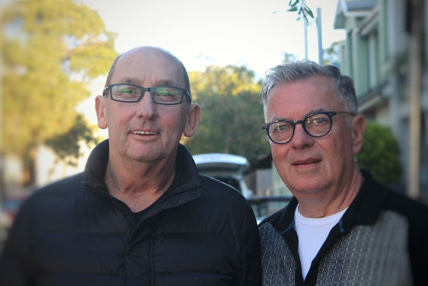 Two men wearing glasses look at camera
