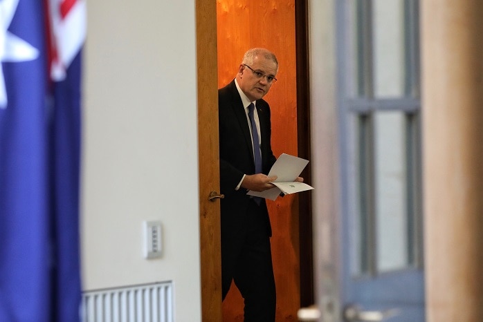 Scott Morrison walking through his office door shuffling papers