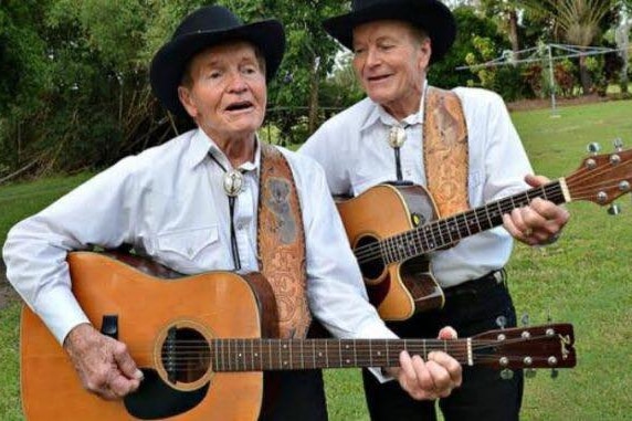 two men in matching clothes play guitar