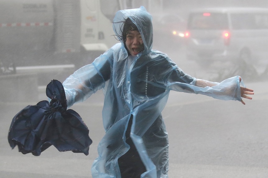 A woman runs in the rainstorm as Typhoon Mangkhut approaches.