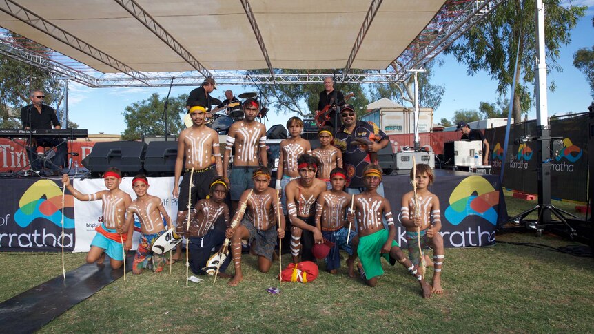A group of young Aboriginal boys and men stand with dance teacher Patrick Churnside at the Roebourne school oval