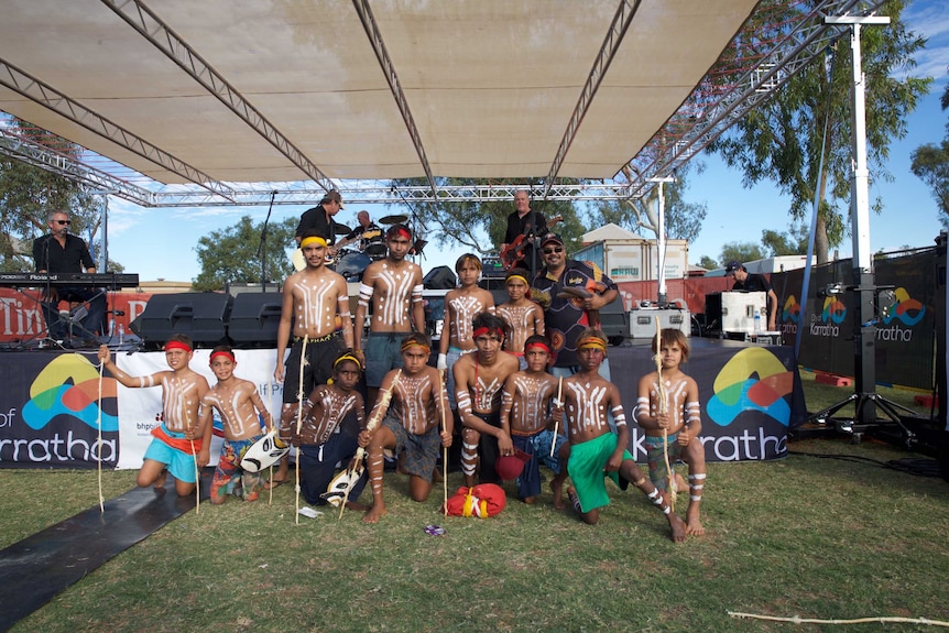 A group of young Aboriginal boys and men stand with dance teacher Patrick Churnside at the Roebourne school oval