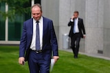 Deputy Leader Barnaby Joyce walks in the courtyard of Parliament House with his head down