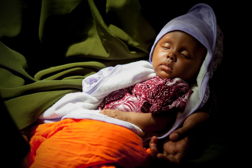 A child sleeps at a UNICEF vaccination clinic in Somalia