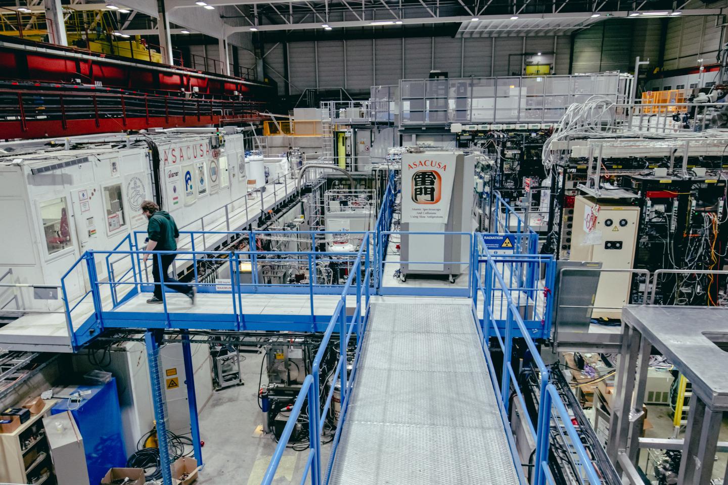 A technician moves along a walkway above the ground level experiments of the factory
