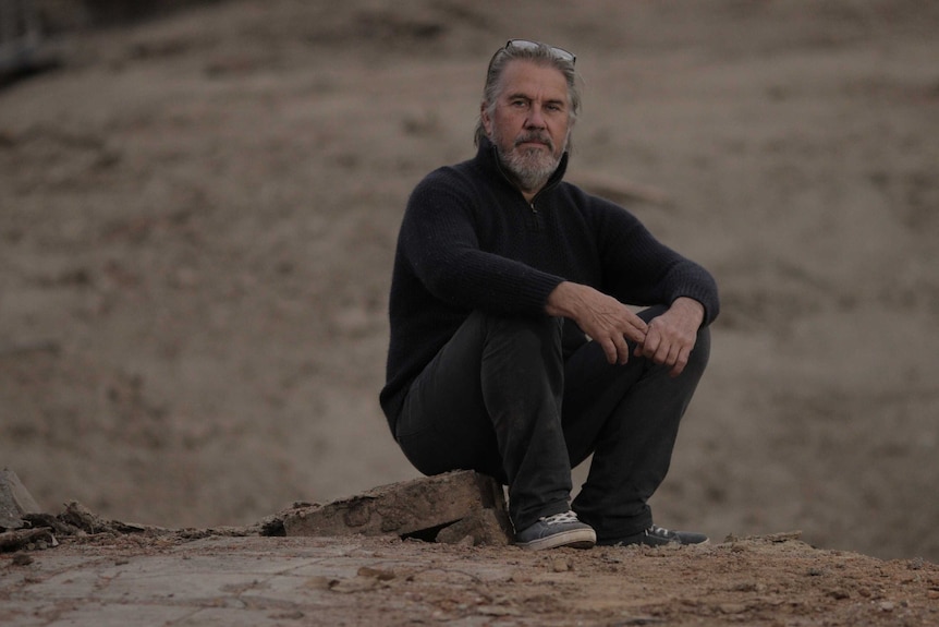 A man sits on a cement path.