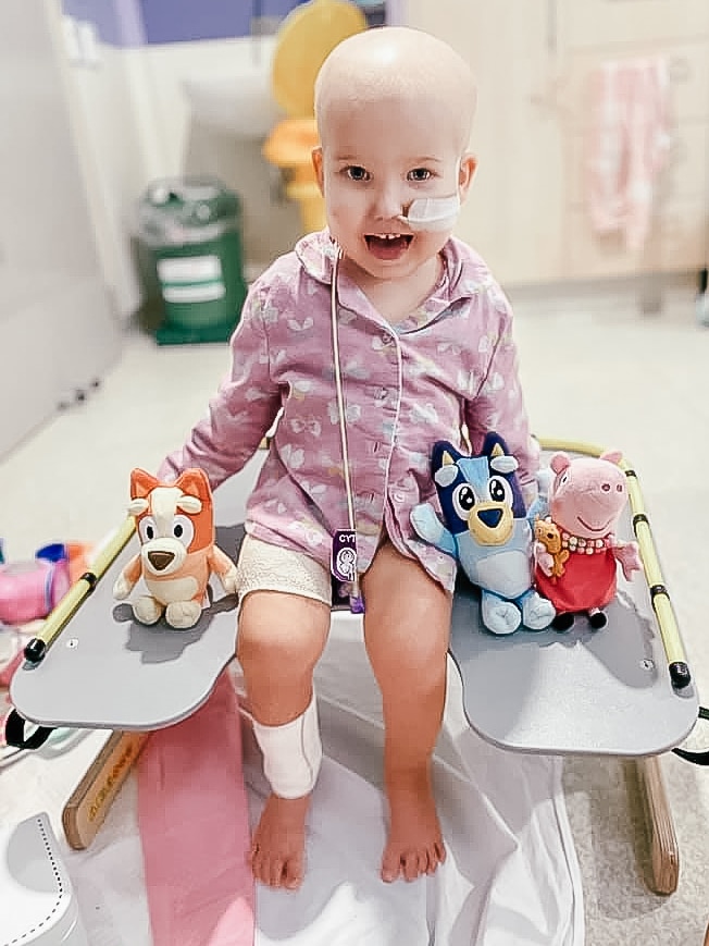 a young girl in hospital with plush bluey and bingo and peppa pig