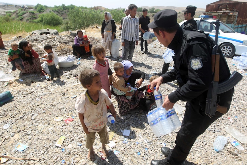 Peshmerga forces hand out water bottles to displaced Iraqi families from the Yazidi community.