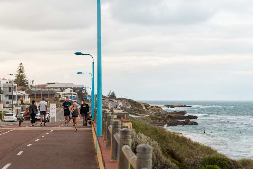 People exercising on a path along a stretch of coast