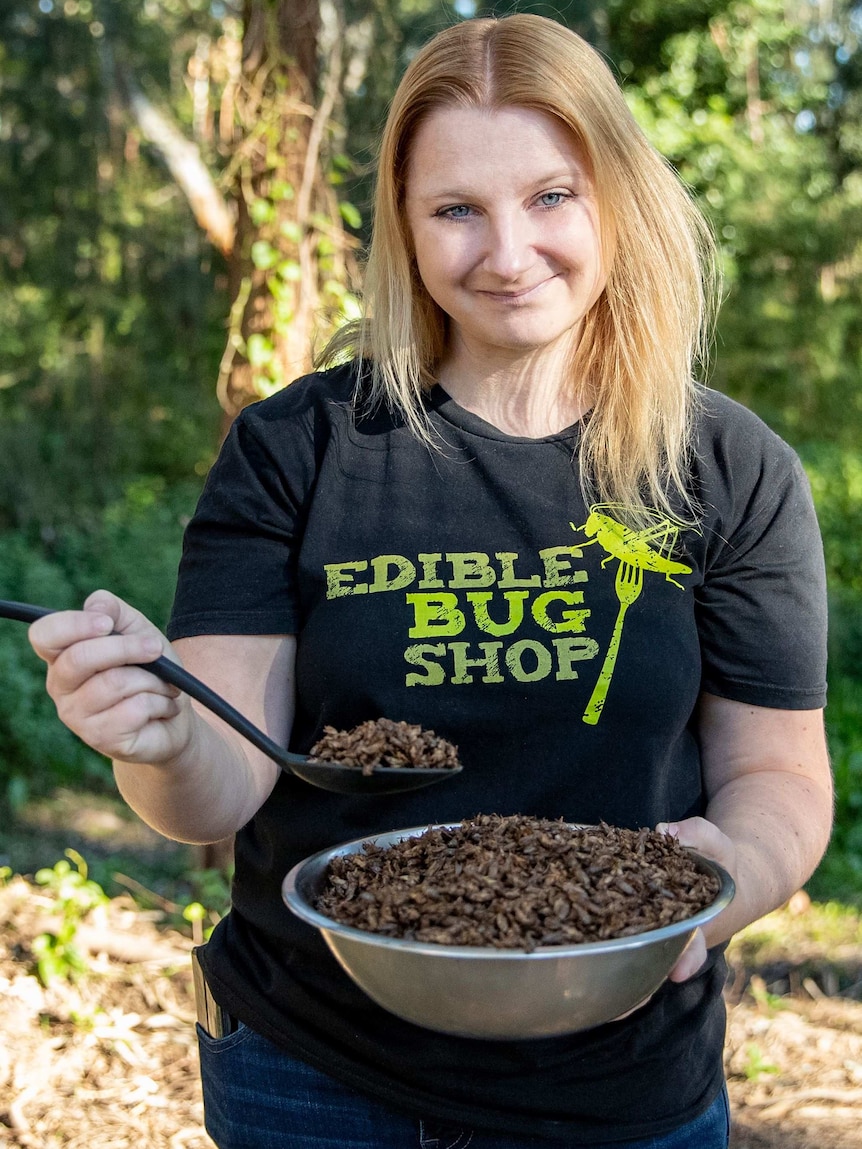 A woman standing outside with a bowl full of crickets.