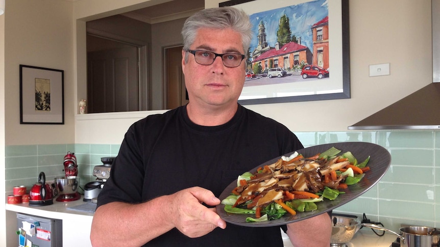 a man holding a plate of stir fried abalone