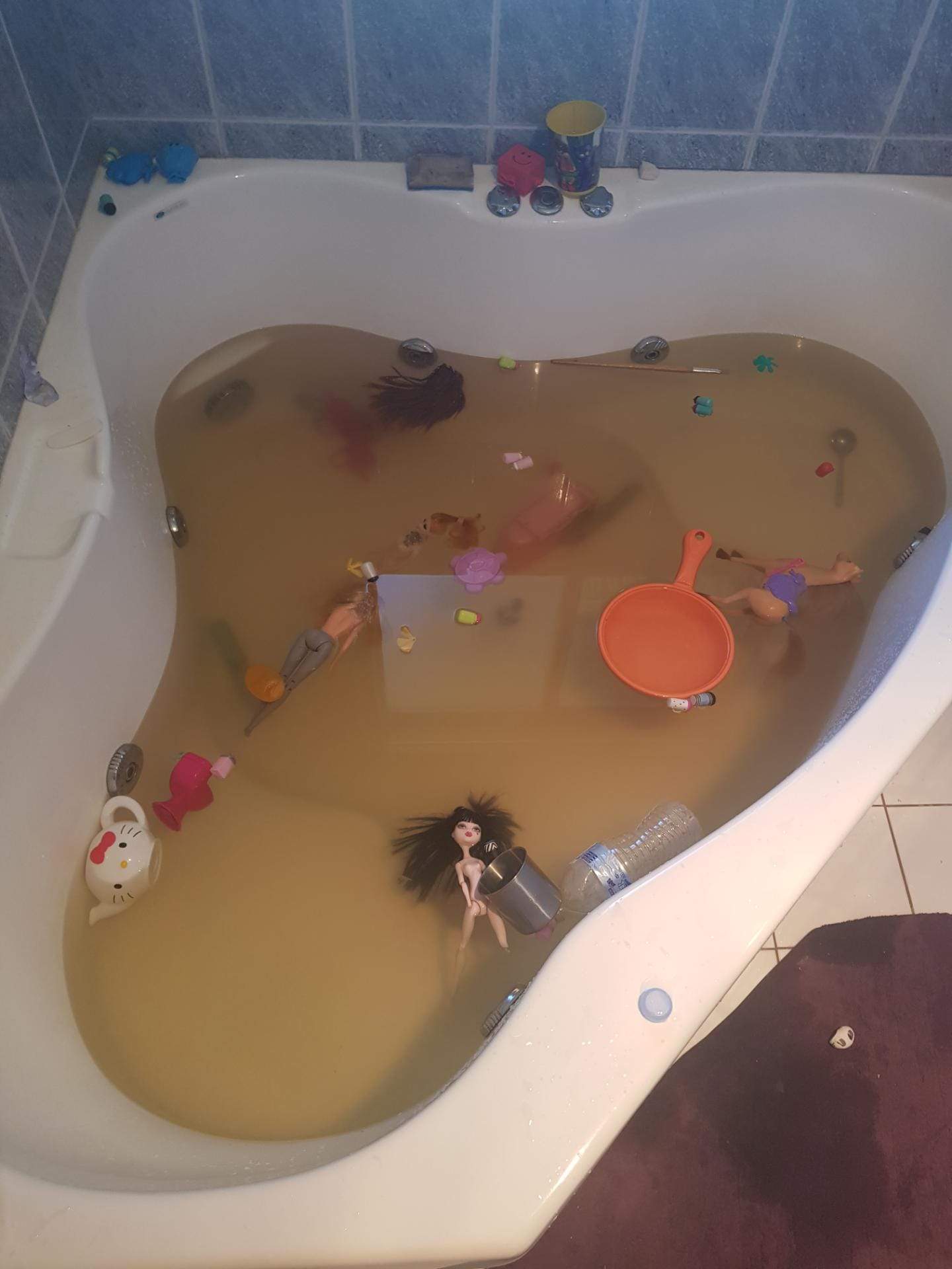 A bathtub full of brown water, with toys floating in it.