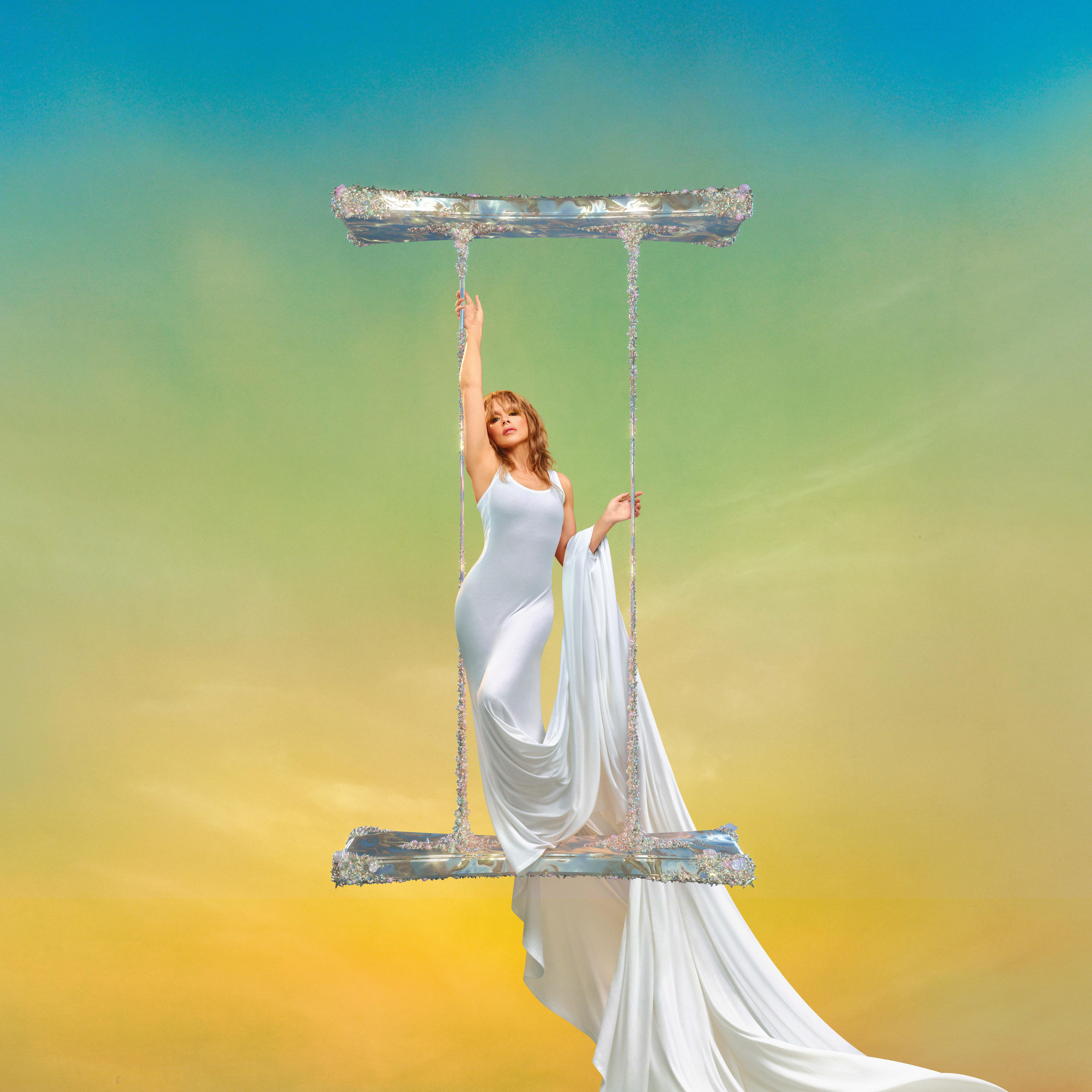 Kylie Minogue in a white dress on a swing for her new album's cover image.