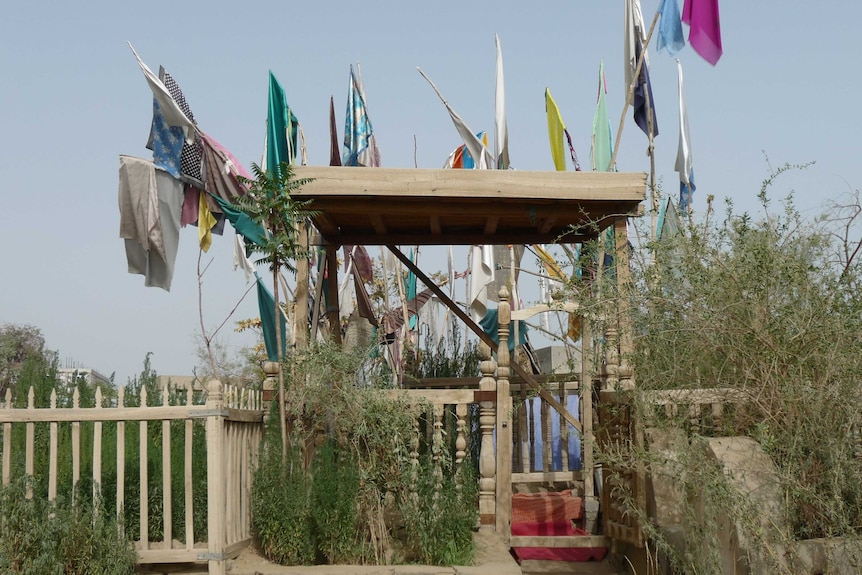 A grave site with multi-coloured flags.