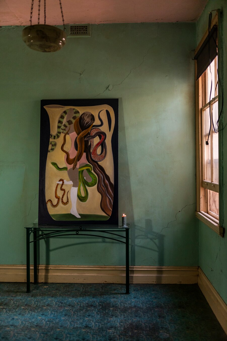 A dimly lit room with a painting resting on a table next to a lit candle