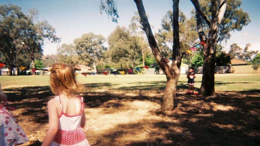 A young girl looks at bunting in park