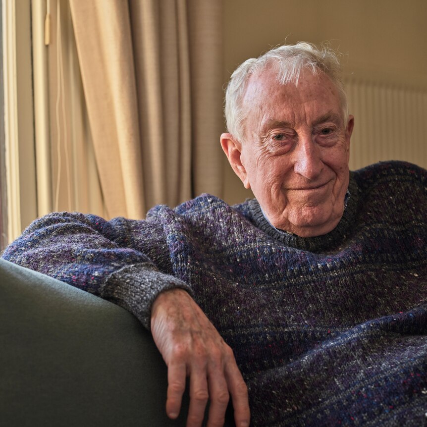 Peter Doherty smiles while sitting on his couch at his home.