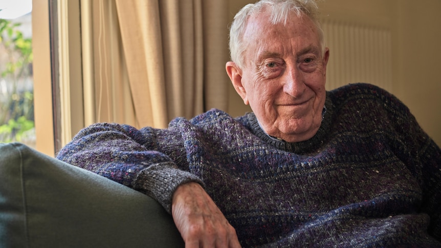 Peter Doherty smiles while sitting on his couch at his home.