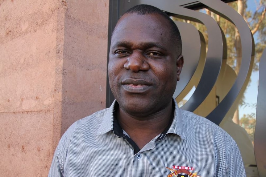 Medium shot of CEO of RAMS Robby Chibawe in front of an artistic metal window