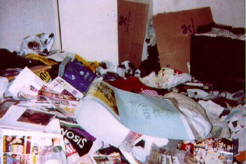 A photo of a hoarders house piled with magazines and cardboard rubbish