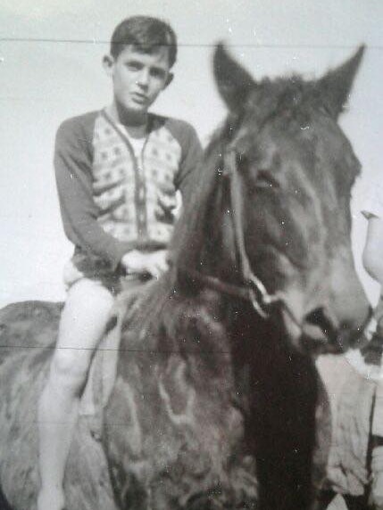 Black and white portrait of a young boy on a horse.