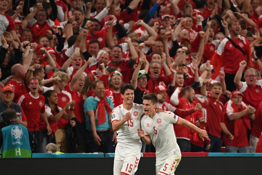 Danish football fans roar in approval as Joakim Maehle and his teammate celebrate a goal for the Danes at Euro 2020. 