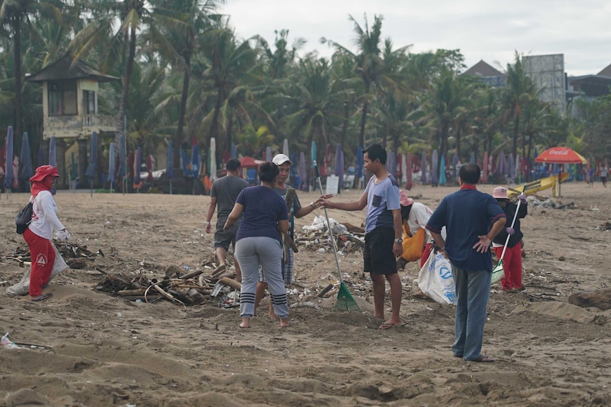 People clean up garbage on a Bali beach