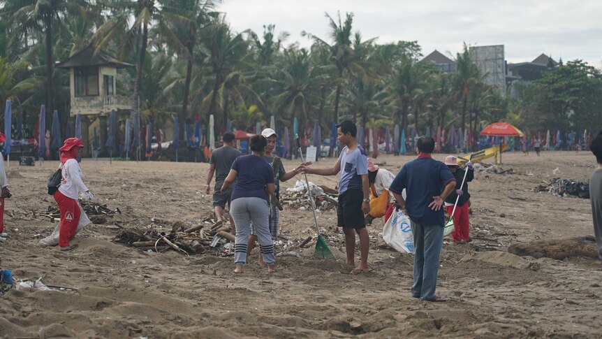 People clean up garbage on a Bali beach