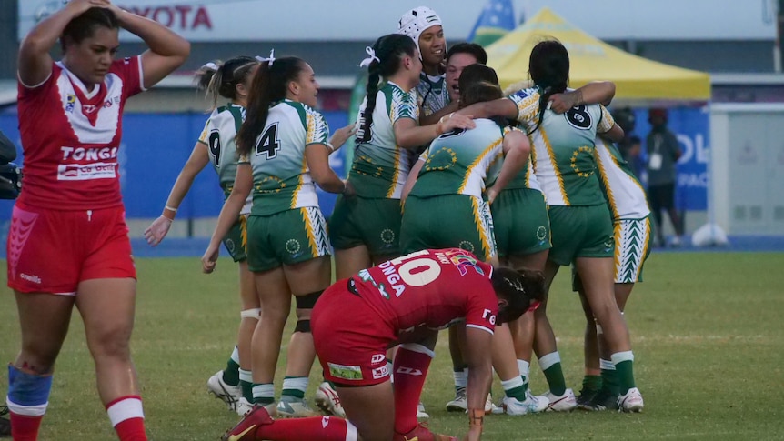 A group of Cook Islands players celebrate while Tongan players look dejected.