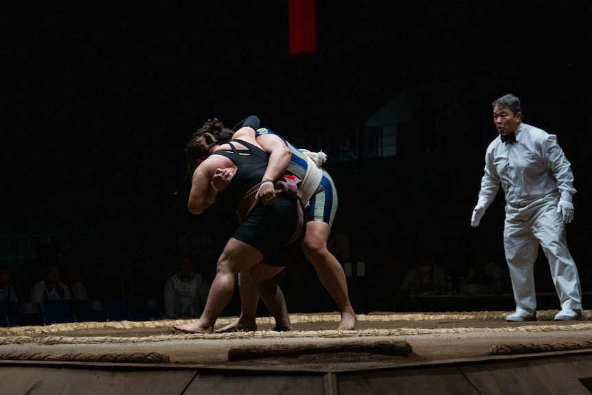 Two women wrestling, with one starting to stumble back 
