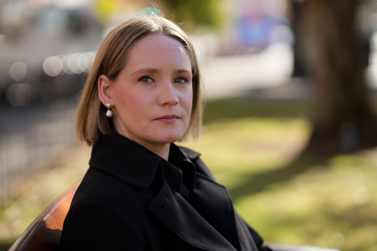 Laura Henderson, SA Shadow Child Protection Minister, sits on a park bench and looks at the camera with a serious face