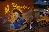 A mural with the words El Pibe de Oro (the Golden Boy) on a Rio de Janeiro wall as a boy cycles by.