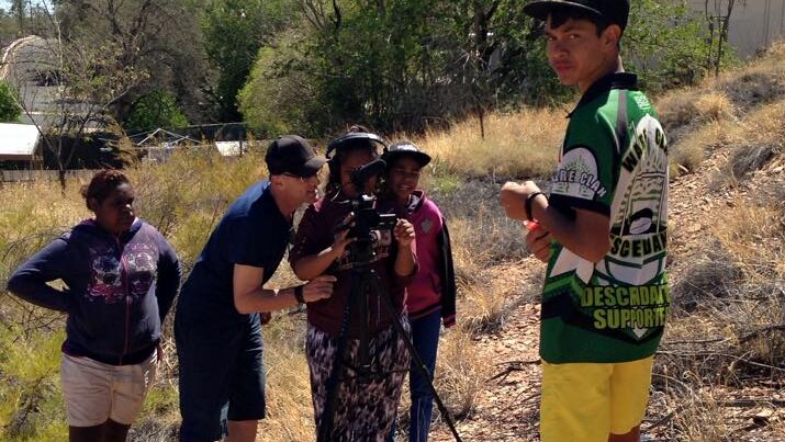 Young Indigenous people look through a move camera