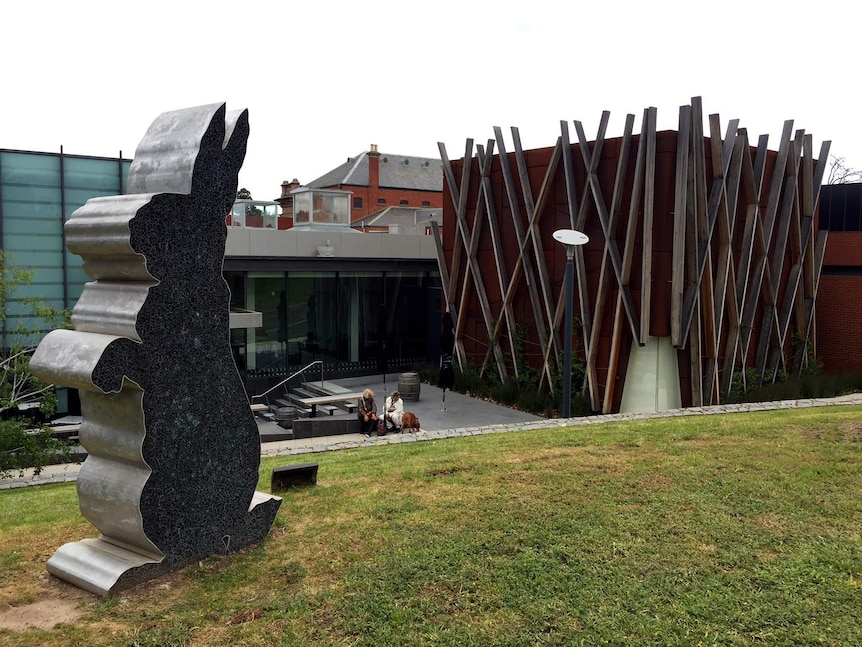 A large rabbit-shaped sculpture with a modern glass and stone building behind it.
