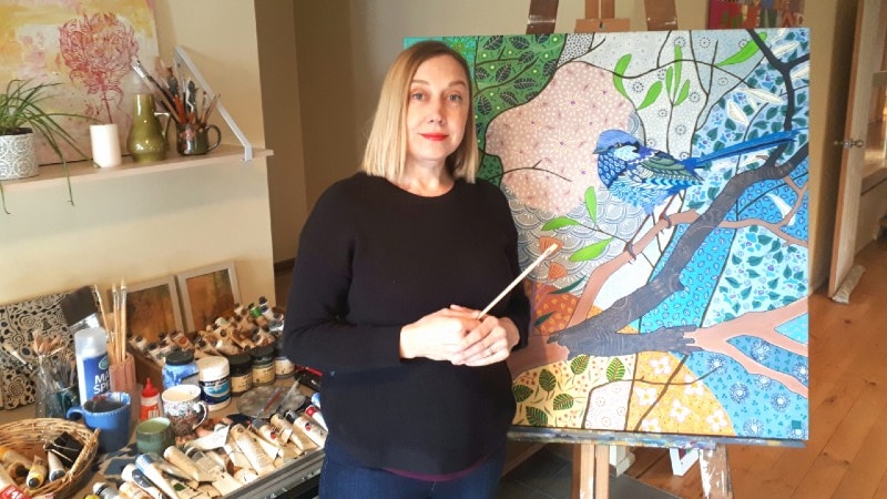 A woman in front of painting canvases.