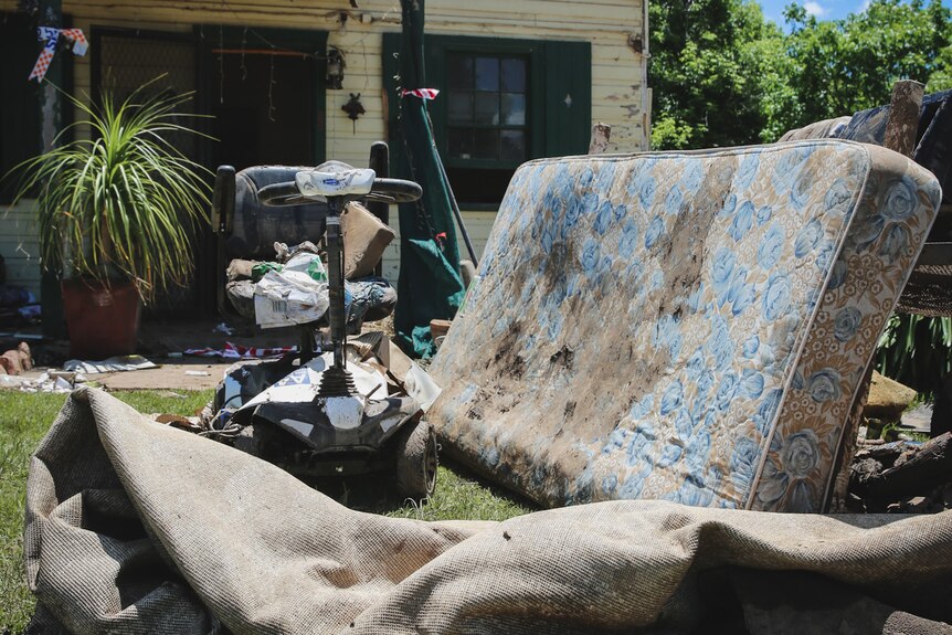 dirty mattress among rubbish strewn across lawn