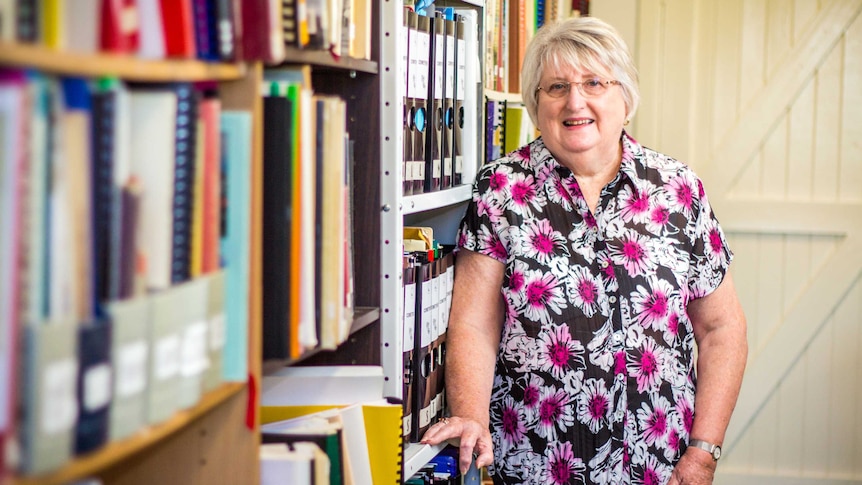 Denise Gaudion stands next to a bookcase.