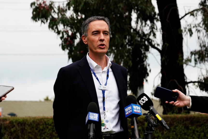 A man in a suit addressing the media.