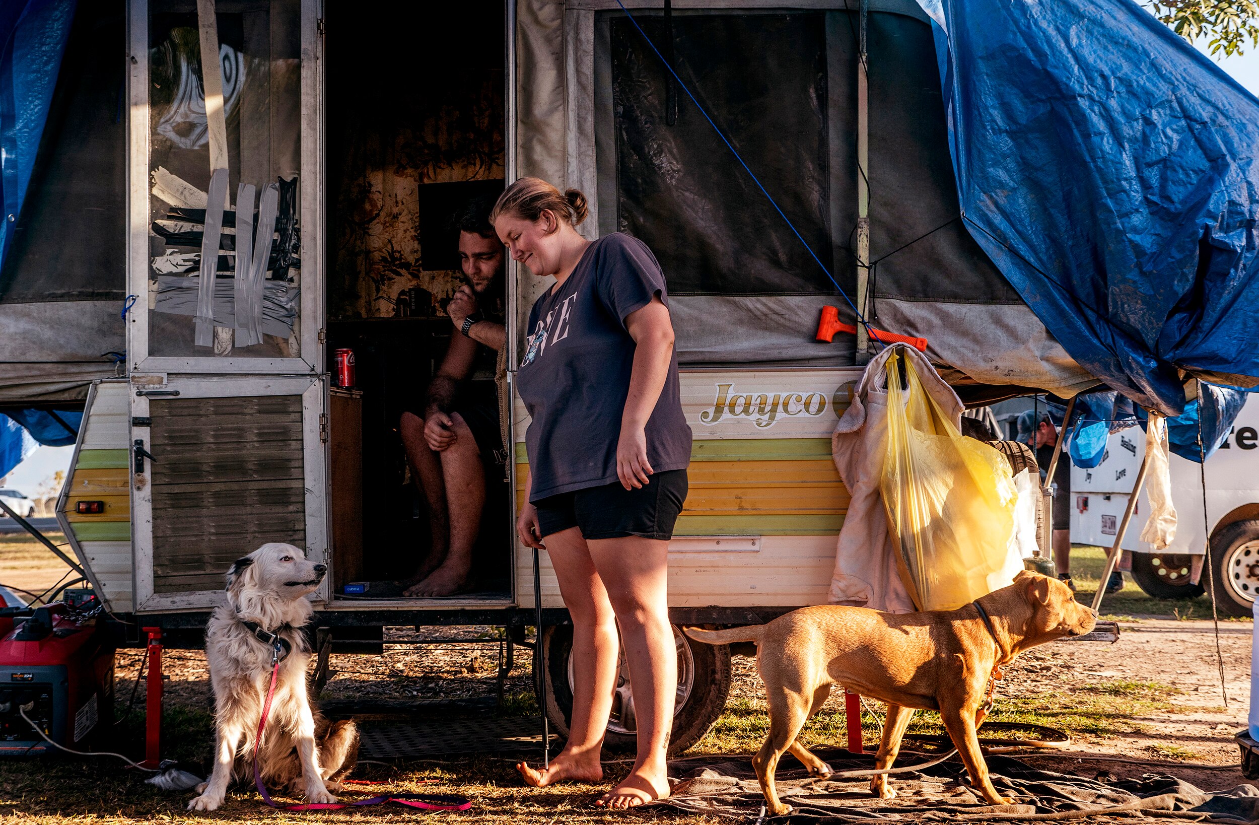 A man and woman outside a caravan with two dogs.