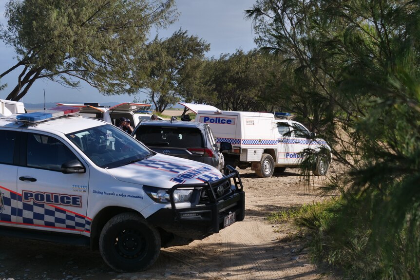 Police cars and officers at a beach.