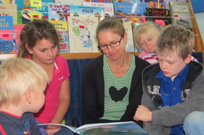 Children and a teacher read books from the School of the Air at Longreach