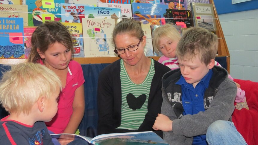 Children and a teacher read books from the School of the Air at Longreach